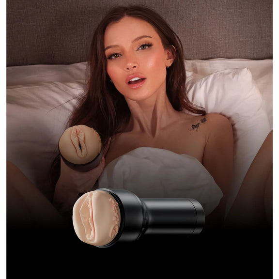 Dainty stares at the camera in just a white bedsheet, holding the FeelStars FeelDainty Stroker towards the camera. | Kinkly Shop