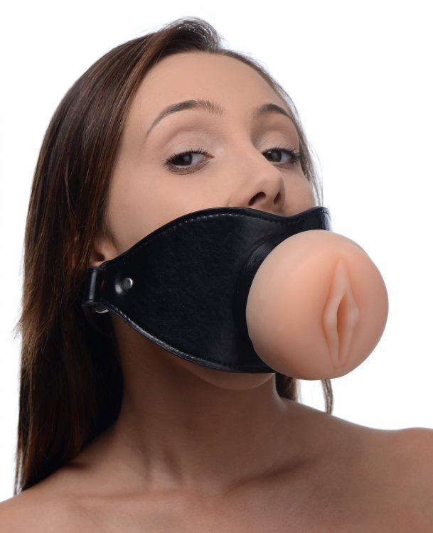A person wears the Master Series Pussy Face gag. The black faux leather strap takes up all of their face from nose down to chin. | Kinkly Shop