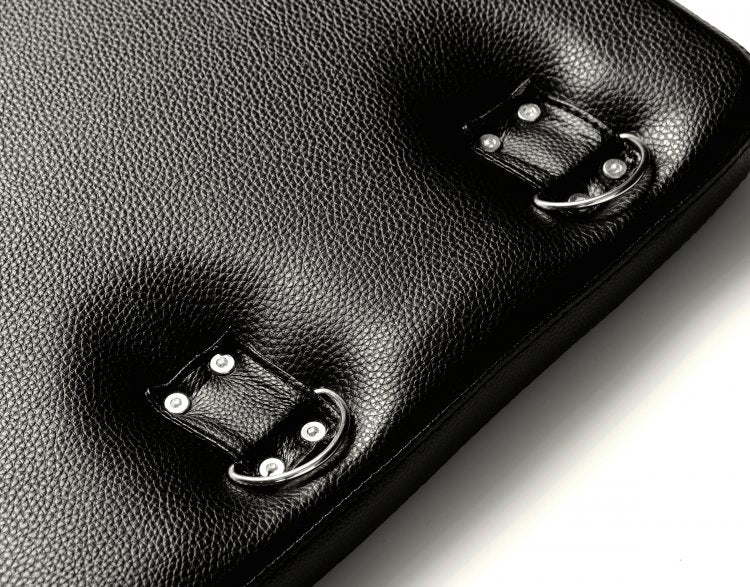 Close-up on the D-rings built into the Strict Bondage Board itself. They are held in place by four rivets and a full strap of fabric that allows for movement of the D-rings. | Kinkly Shop