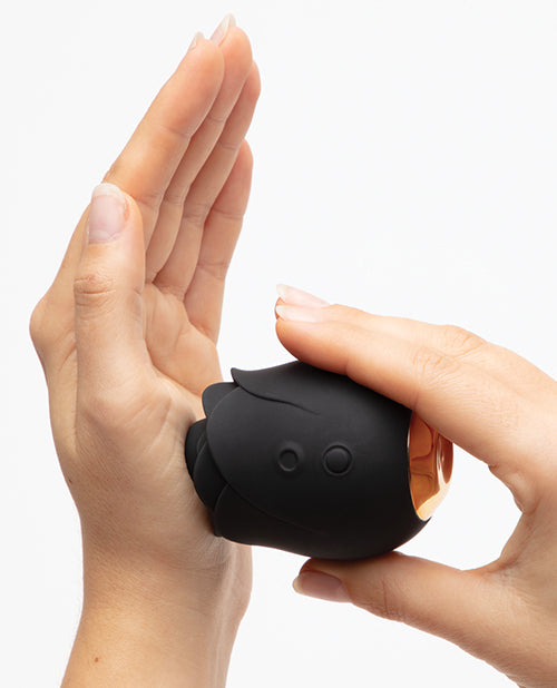 Two hands are shown. One hand is holding the base of the Hearts & Flowers Rose, pushing it onto the palm of the other hand, showcasing how the clitoral tip surrounds an area for pleasure. | Kinkly Shop