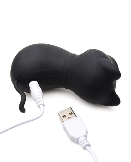The Inmi Shegasm Sucky Kitty lays on its side, showcasing the charger plugged into the backside of the cat. It's a pin-style charger that needs to go into the toy's surface. | Kinkly Shop