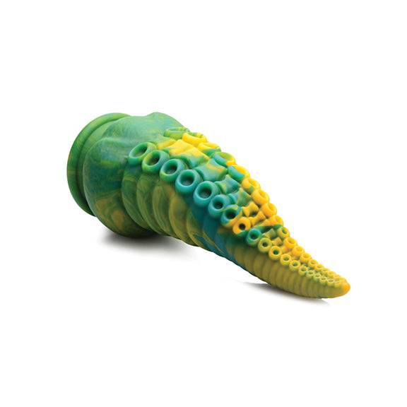 The Creature Cocks Monstropus lays on its side. The dildo looks really thick and it is lifted off the ground. This showcases the firm inner core that helps the dildo hold its position. | Kinkly Shop