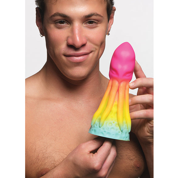 A person holds the Creature Cocks King Kraken between their hands. It looks like average length but very VERY thick near the base. It has a cute rainbow ombre color. | Kinkly Shop