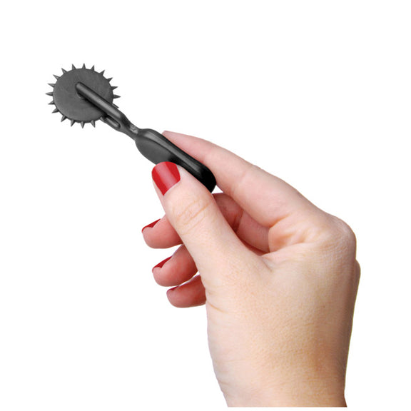 A hand holds the Lil Devil Plastic Sensation Wheel. It is very small, less than the length of the person's palm and smaller than many bullet vibrators. | Kinkly Shop