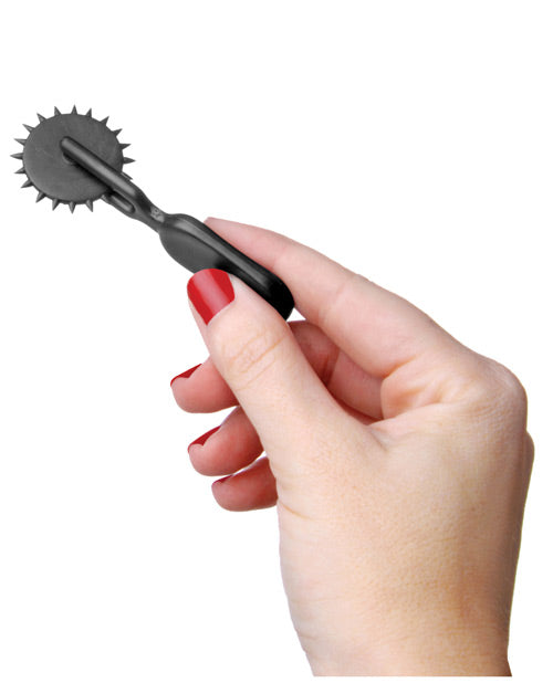 A hand holds the Lil Devil Plastic Sensation Wheel. It is very small, less than the length of the person's palm and smaller than many bullet vibrators. | Kinkly Shop