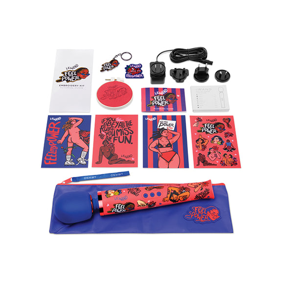 Everything included with the Le Wand Feel My Power: Kelly Malka gift set. There are stickers, postcards, keychains, instruction manuals, embroidery, a branded zipper pouch, the vibrator, and the charger with all of its international adapters. | Kinkly Shop