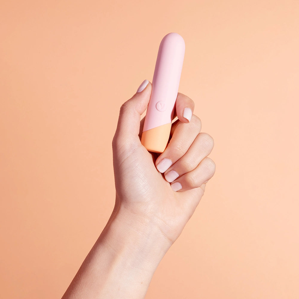 A hand holds the VUSH Peachy Bullet. The toy is relatively short and slender, though larger than some other bullet vibrators. | Kinkly