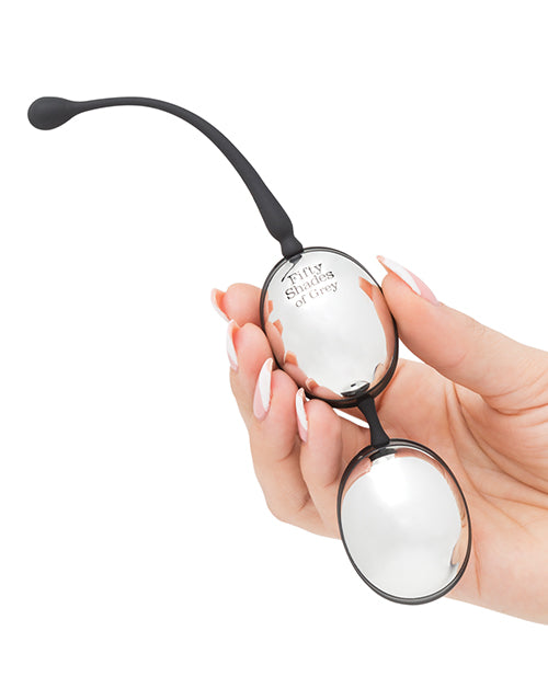 A hand holds the Inner Goddess Jiggle Balls. The silver, mirrored paint on the plastic kegel balls makes for a mirrored view. | Kinkly Shop