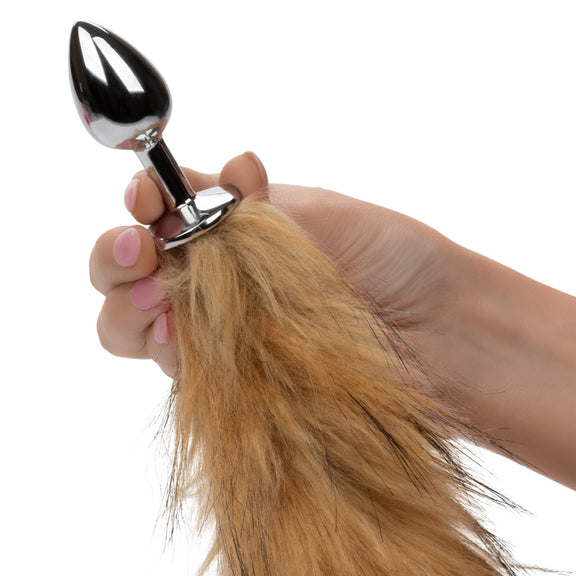 A hand holds the metal plug of the Running Wild Tail Plug up to the camera. It's a standard, very small butt plug made from metal. | Kinkly Shop