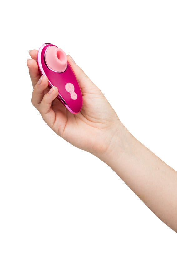 A hand holds the Womanizer x Iggy Azalea Liberty 2. The toy is very small, easily fitting within the palm of their hand. Their fingers curve around the size of the Womanizer x Iggy Azalea Liberty 2 easily. | Kinkly Shop