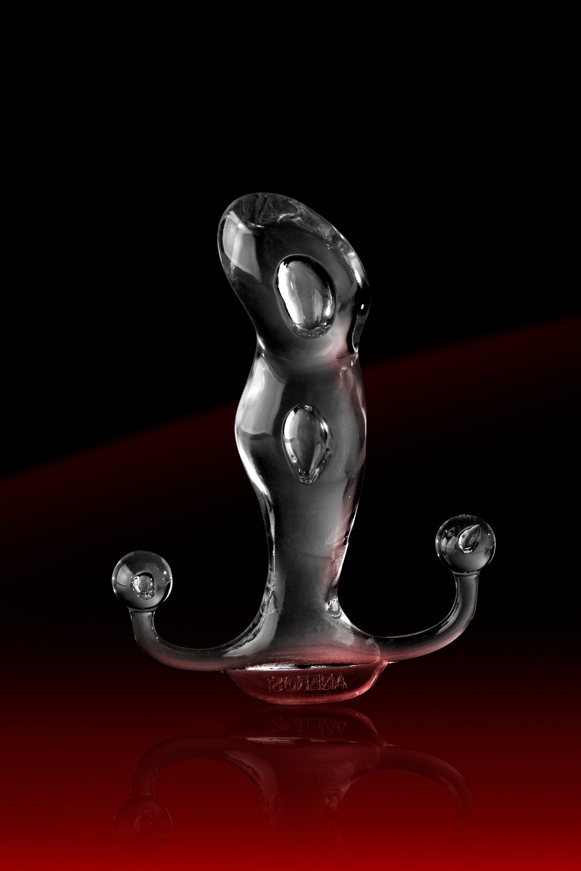 The Aneros Progasm Ice in front of a black and red background. The light shimmers in front of the black background, showcasing the see-through, clear design of the massager. | Kinkly Shop