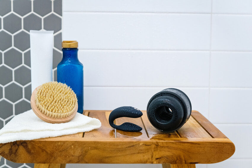 The Arcwave Voy and the We-Vibe Sync 2 laying out on top of a shower stool, dripping with water droplets. | Kinkly Shop