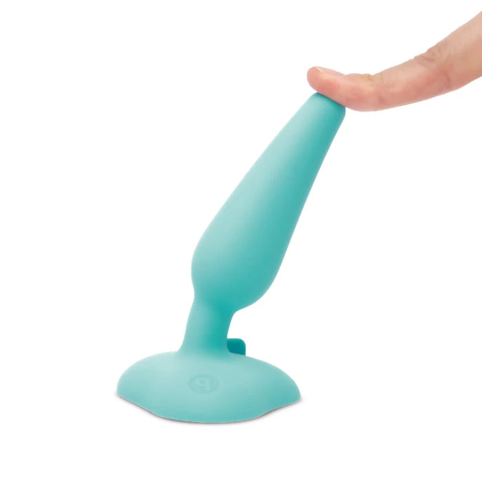 One of the plugs is suction cupped to a flat surface. A hand pulls at the tip of the plug, showcasing how the toy stays adhered despite being pulled off to the side. | Kinkly