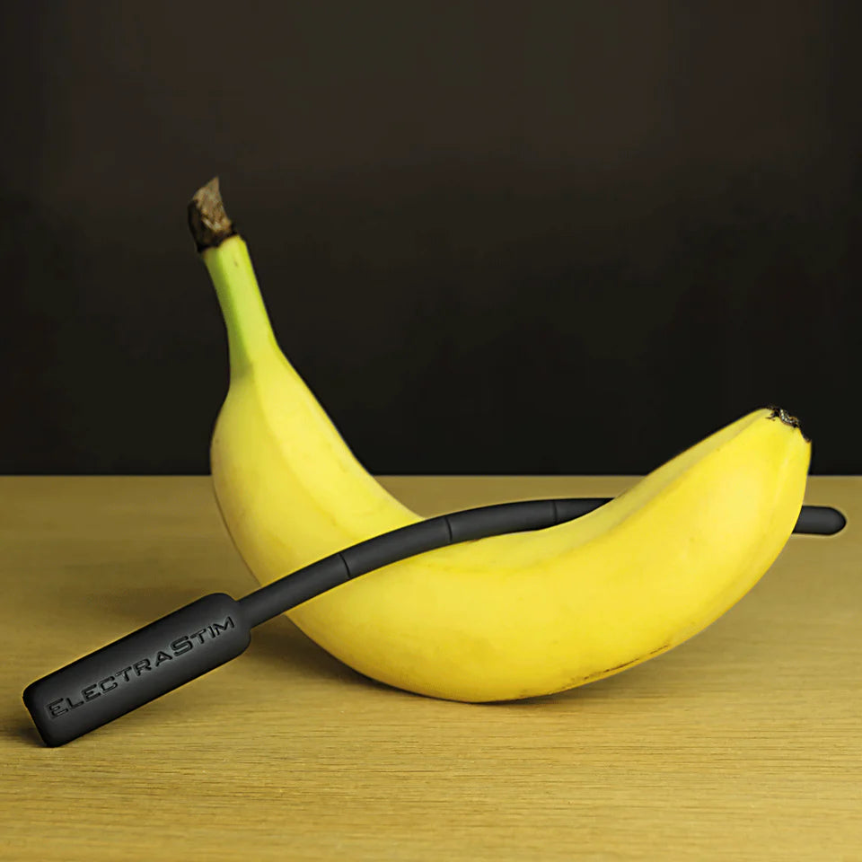 The ElectraStim Flexible Electro Sound draped over a banana. The sound has a slight curve to it as the flexible design means the sound doesn't stay fully rigid. | Kinkly