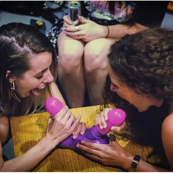 Two people smiling as they hold their open mouths on tips of the penis penises on the Cum Face Game. | Kinkly Shop