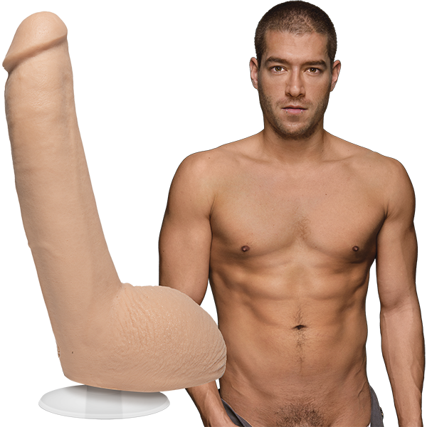 A naked Xander Corvus stares into the camera. The Signature Cocks - Xander Corvus dildo is shown next to Xander, which is modeled directly from the Xander's erect length. | Kinkly Shop
