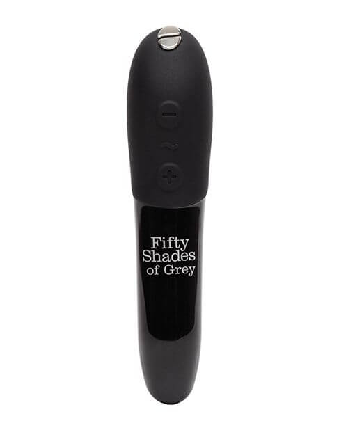Close-up of the Fifty Shades of Grey Come to Bed Kit's We-Vibe Tango X. The vibrator is entirely black aside from the "Fifty Shades of Grey" written words printed on the shaft of the vibrator. The top half, with the buttons and where you hold the vibrator, is made from a matte, easy-grip silicone. The bottom half of the vibrator is made from a glossy, shiny plastic that easily transfers vibrations. | Kinkly Shop