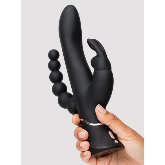 A hand holds the Happy Rabbit Triple Curve. It looks very formidable with a lot of ways to experience pleasure right at the palm of their hand. | Kinkly Shop
