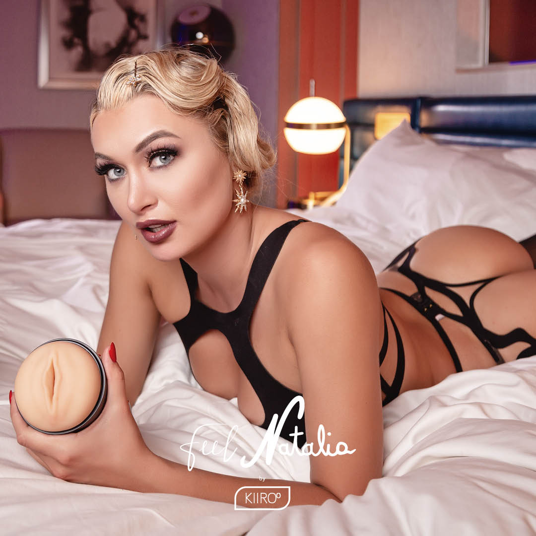 Natalia Starr, with immaculate hair, looks into the camera, holding the FeelStars FeelNatalia Stroker. | Kinkly Shop