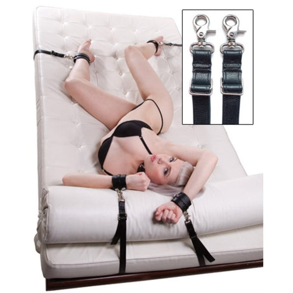 A person lays out on top of a chaise lounger. The KinkLab Bedspread Restraint System is set up underneath the lounger, allowing the person's wrists and ankles to be bound to the lounger. The claw-style clasps are shown in a close-up shot in the corner of the image. | Kinkly Shop