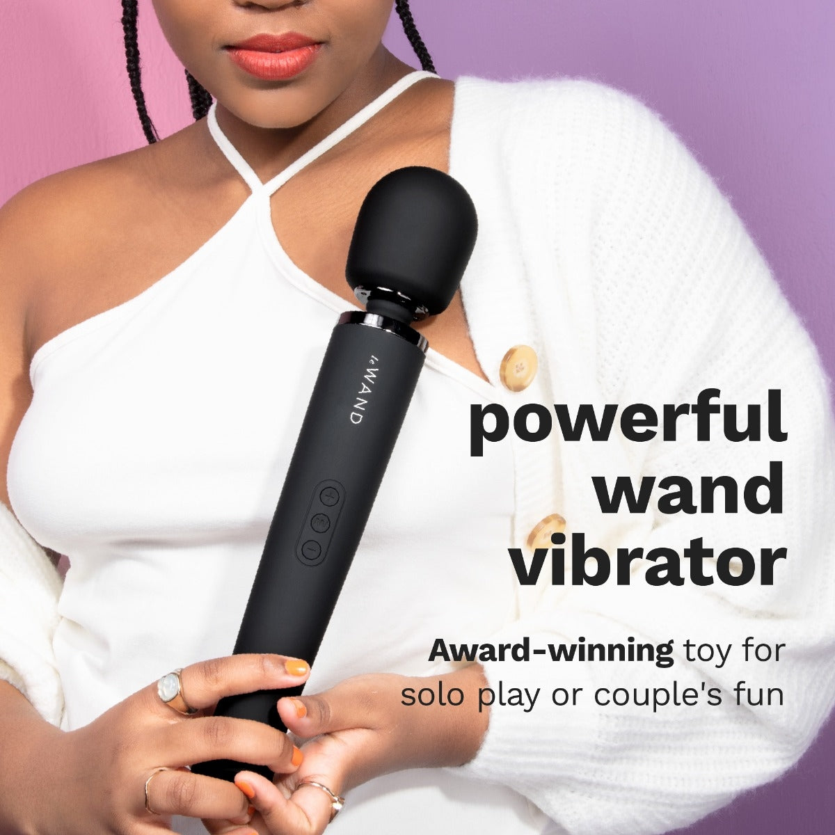 A person holds the Le Wand Rechargeable Wand in Black in front of their chest. The wand massager is very long, about as long as their ribcage. Text on the image reads: "Powerful wand vibrator. Award-winning toy for solo play or couple's fun." | Kinkly Shop