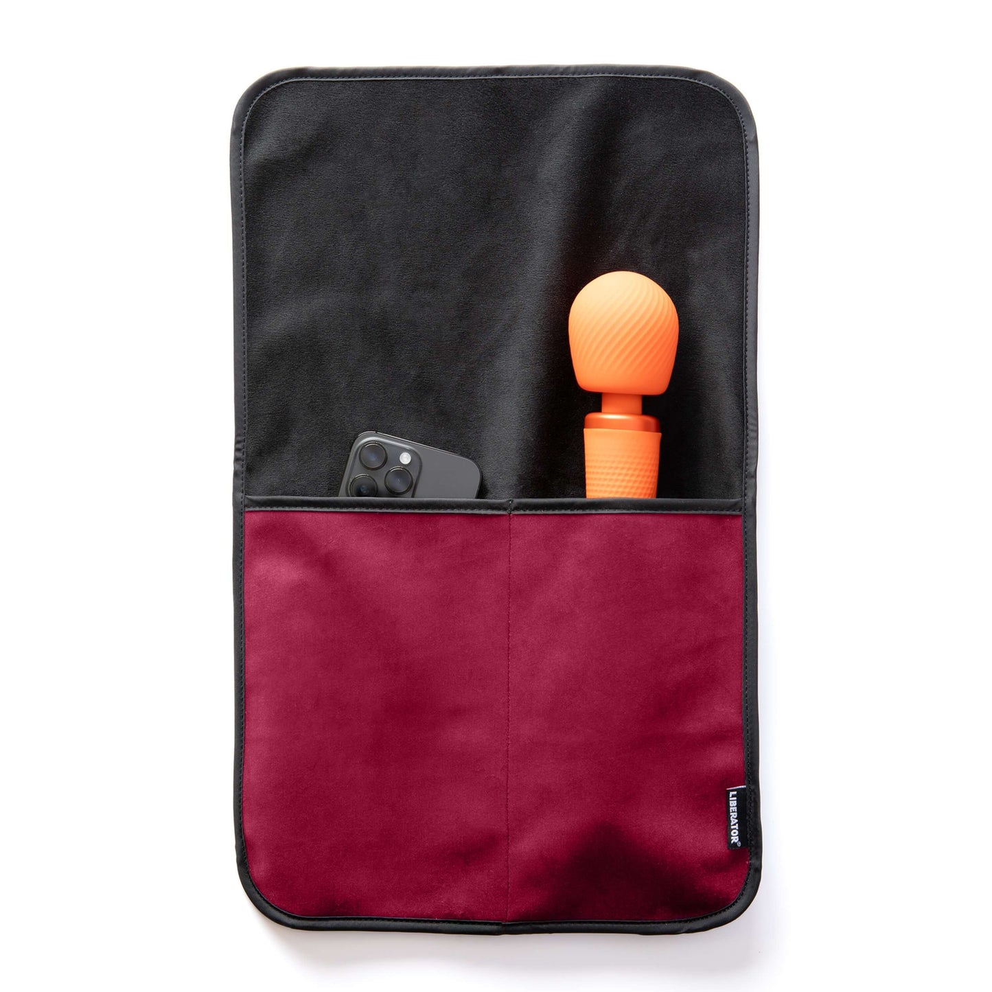 The Liberator Fascinator Sex Toy Caddy in Merlot laying flat on a white surface. A wand massager and a cell phone are shown peeking out from the tops of the pockets. The full length of the wand massager fits within the deep pocket, leaving only the massager's head showing from the pocket. | Kinkly Shop