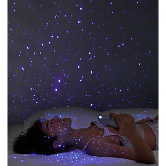 A person holds the Svakom Pulse Galaxie on their chest, allowing the vibrator to project a starry night projection onto the bedroom around them | Kinkly Shop