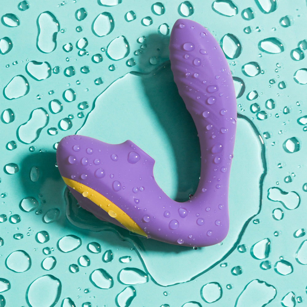 The ROMP Reverb laying on top of a blue surface filled with water droplets. The vibrator is covered in water droplets as well. | Kinkly Shop