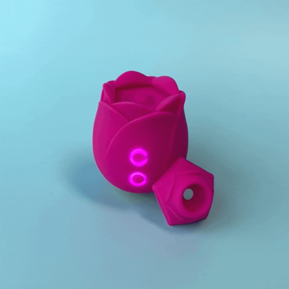 The ROMP Rose in front of a blue background. There are two buttons on the front of the Rose. Those buttons are backlit by a blue lighted ring. The air suction tip is shown pulled out out of the tip of the toy. | Kinkly Shop