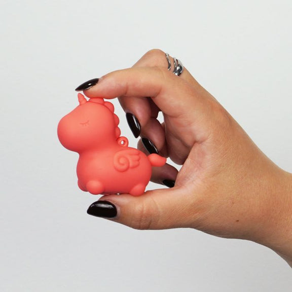 A person holds the Unihorns Mini Peachy Pony between their two fingers. The toy is very small, shorter than the height of a finger, and looks really cute in the person's hands. | Kinkly Shop