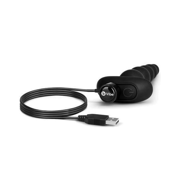 The b-Vibe Cinco Remote Control Rechargeable Beads is laying down with the magnetic charger attached to its base. The other side of the charging cord features a USB plug. | Kinkly Shop