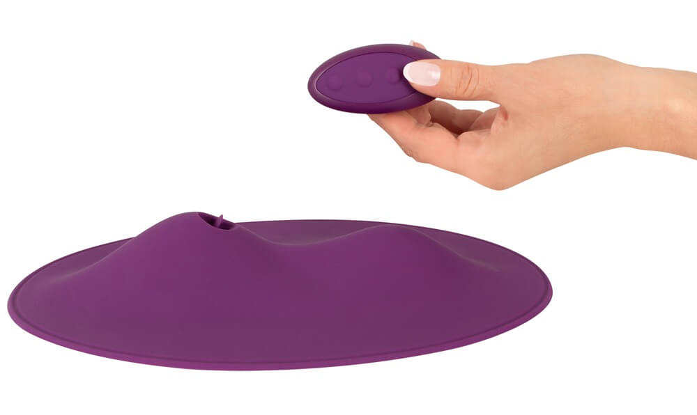 A hand holds the remote over top of the Orion VibePad 2. The remote is the perfect size to fit into the palm of a hand. | Kinkly Shop