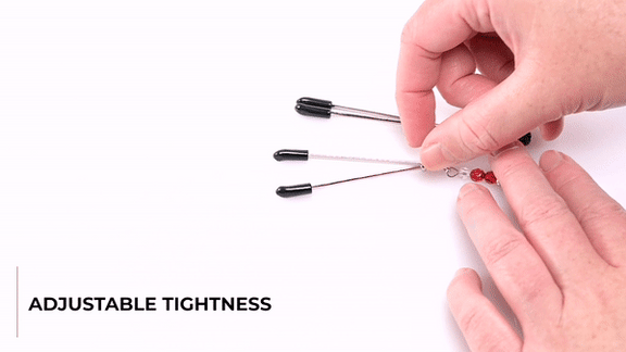 GIF showing someone handling the Sportsheets Ruby Black Nipple Clamps. The GIF shows the Adjustable Tightness through the rings on the shafts of the nipple clamps. The text says "Rings Slide Down: For Snug-As-You-Like Sensations". | Kinkly Shop