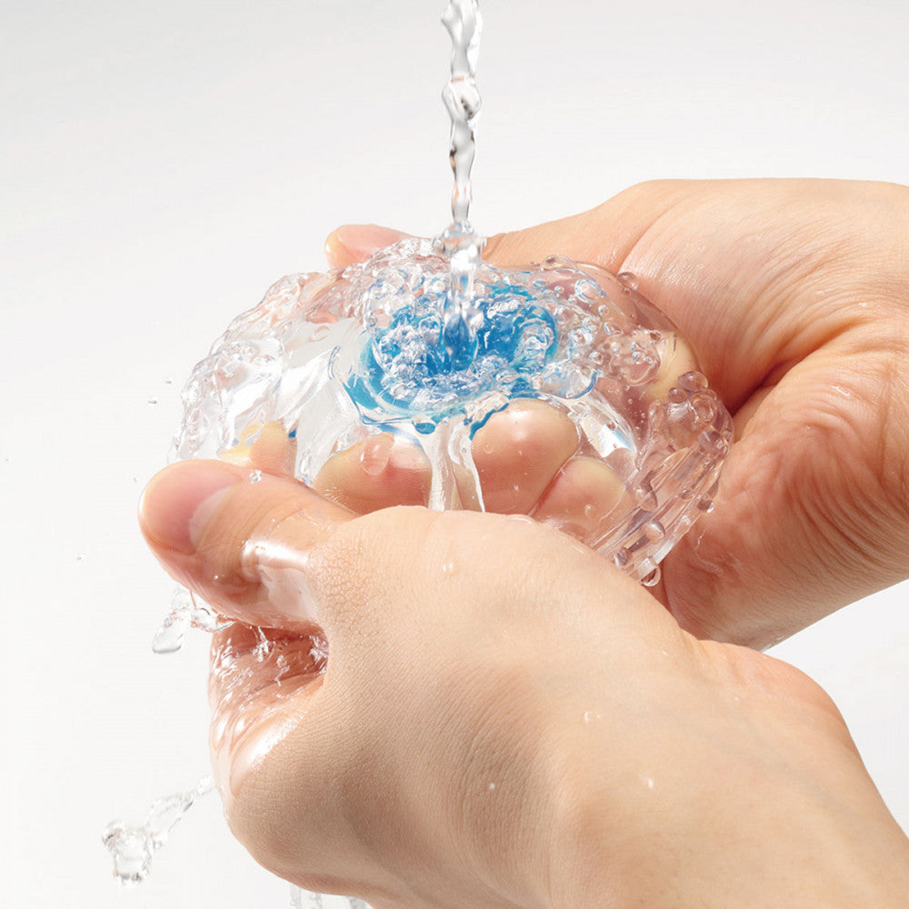 Two hands are holding the Tenga Aero Cobalt's entrance open to allow water to flow through the sleeve for cleaning. | Kinkly Shop