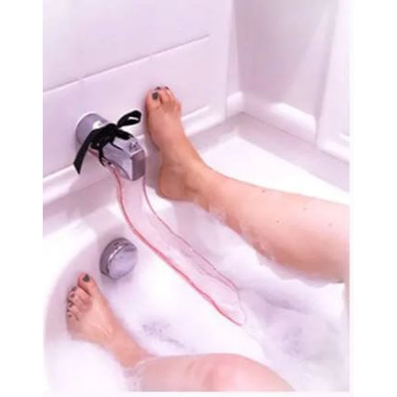 The Waterslyde Bathtub Water Diverter tied onto the water spout. A person's two feet are shown pressed against the shower wall while the Waterslyde Bathtub Water Diverter causes the water to flow between the person's legs. | Kinkly Shop