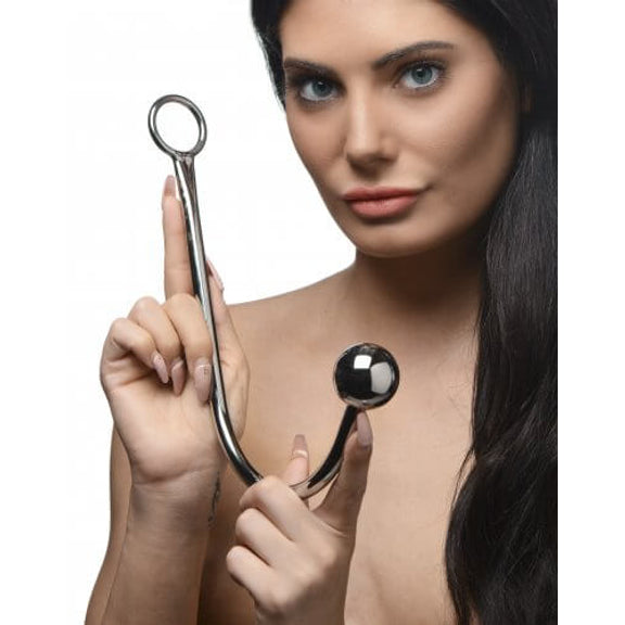 A person is looking straight into the camera while holding the Master Series Stainless Steel Anal Hook with both hands. Perfect as a size reference, this image shows that the anal hook is much longer than the length of a single hand (fingertip to base of palm) and closer to the length of two hands. | Kinkly Shop