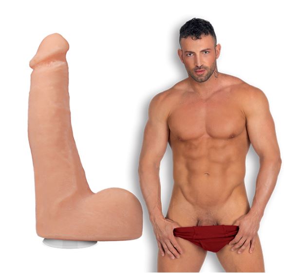 Maximo Garcia in front of a plain white background, pulling down his brief underwear while looking into the camera. The Signature Cocks - Maximo Garcia dildo is shown next to him, lifecast from the porn star. | Kinkly Shop