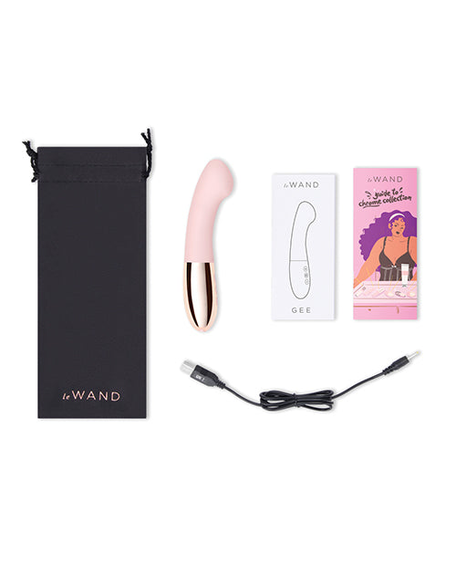 Everything included with the Le Wand Gee vibrator. This includes the drawstring storage bag, the instruction manual, a promotional booklet, and the charging cable. | Kinkly Shop