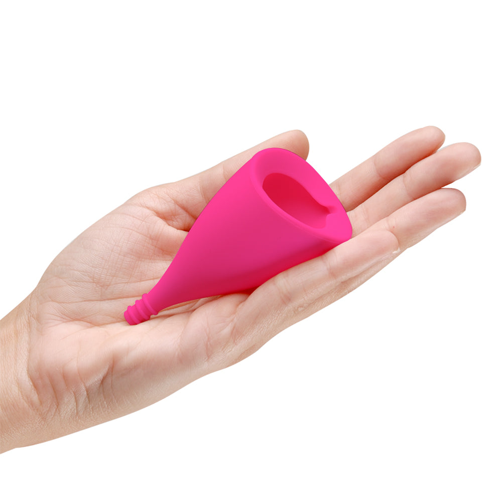 A hand holds the Intimina Lily Cup B in their hand. It looks like a small cylinder. | Kinkly Shop