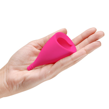 A hand holds the Intimina Lily Cup B in their hand. It looks like a small cylinder. | Kinkly Shop