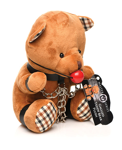 Side angle of the Master Series Gagged Teddy Bear. The teddy bear is wearing wrist cuffs, ankle cuffs, and a collar. | Kinkly Shop