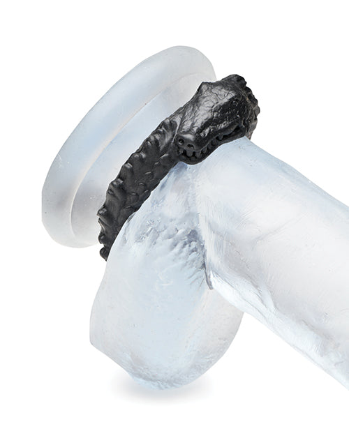 The Creature Cocks Caiman shown wrapped around the base of a clear dildo. It's under the shaft and the testicles, flush up against the fake-body of the dildo. | Kinkly Shop