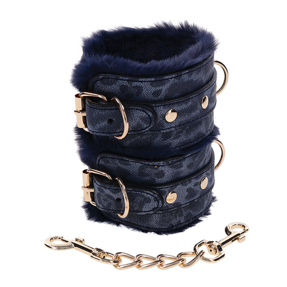 Close-up on the faux leather and faux fur materials on the Sportsheets Cougar Fur Wrist Cuffs. The faux leather has a textured grain to it. The matching gold connector chain is fully detachable from both cuffs. | Kinkly Shop