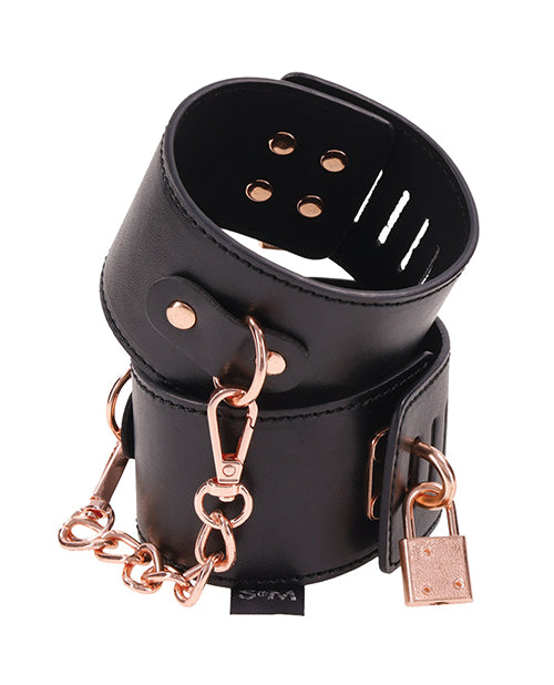The Sportsheets Brat Locking Cuffs looped together and stacked on top of one another. The rose gold metal contrasts beautifully with the black faux leather. | Kinkly Shop