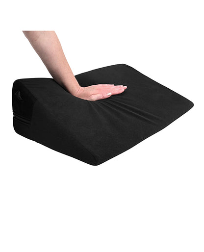 A hand presses firmly down on the top of the Sportsheets Pivot Positioner, showcasing how firm the shape is. It compresses more than competitor shapes, but it still offers quite a bit of upwards boost despite the applied weight. | Kinkly Shop