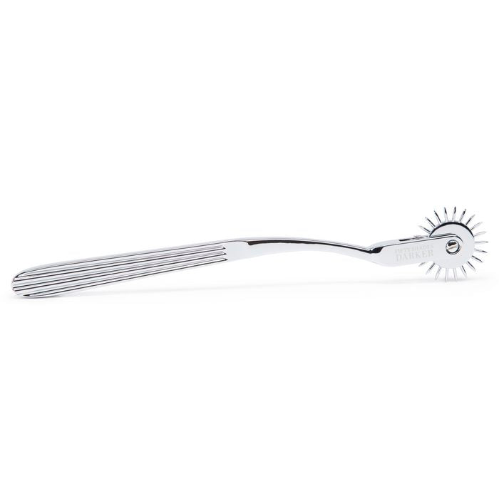 The Fifty Shades "Adrenaline Spikes" Pinwheel lays on a flat surface. The slotted texture of the handle to make it easier to grip is very visible here. | Kinkly Shop