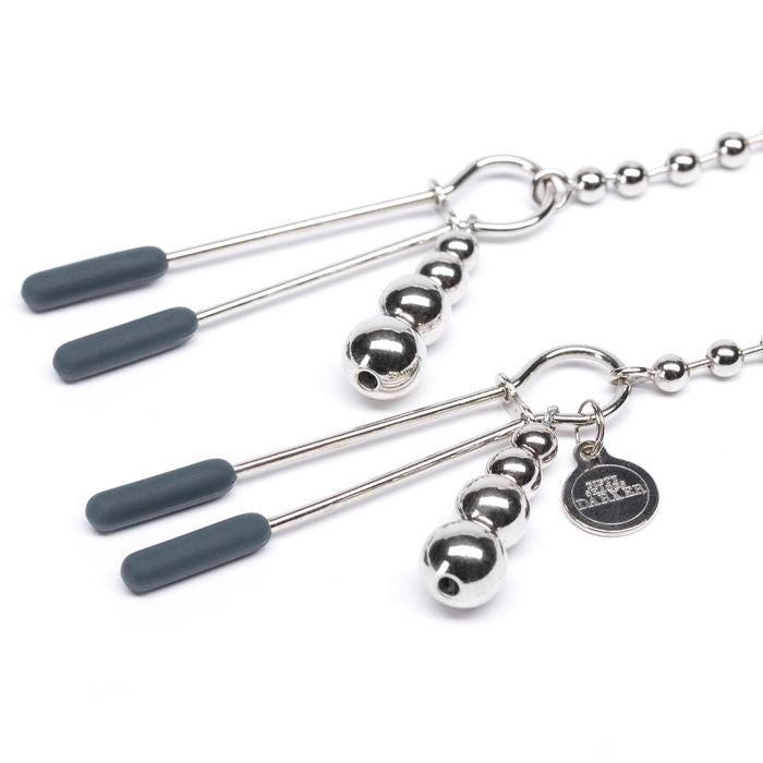 Close-up on the nipple clamps themselves. There are small weights on each clamp with a little charm that says "Fifty Shades Darker" on the clamp. | Kinkly Shop