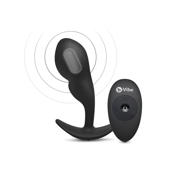 An X-ray vision of the B-Vibe Remote Control P-Spot Snug Plug showcases the vibrating motor inside of the tip of the prostate plug. A small oval-shaped remote nearby showcases that the toy is wirelessly remote controlled. | Kinkly Shop