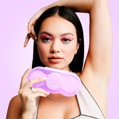 A person holds the VUSH Aura Wireless TENS Device inside of its travel case in front of their face. | Kinkly Shop