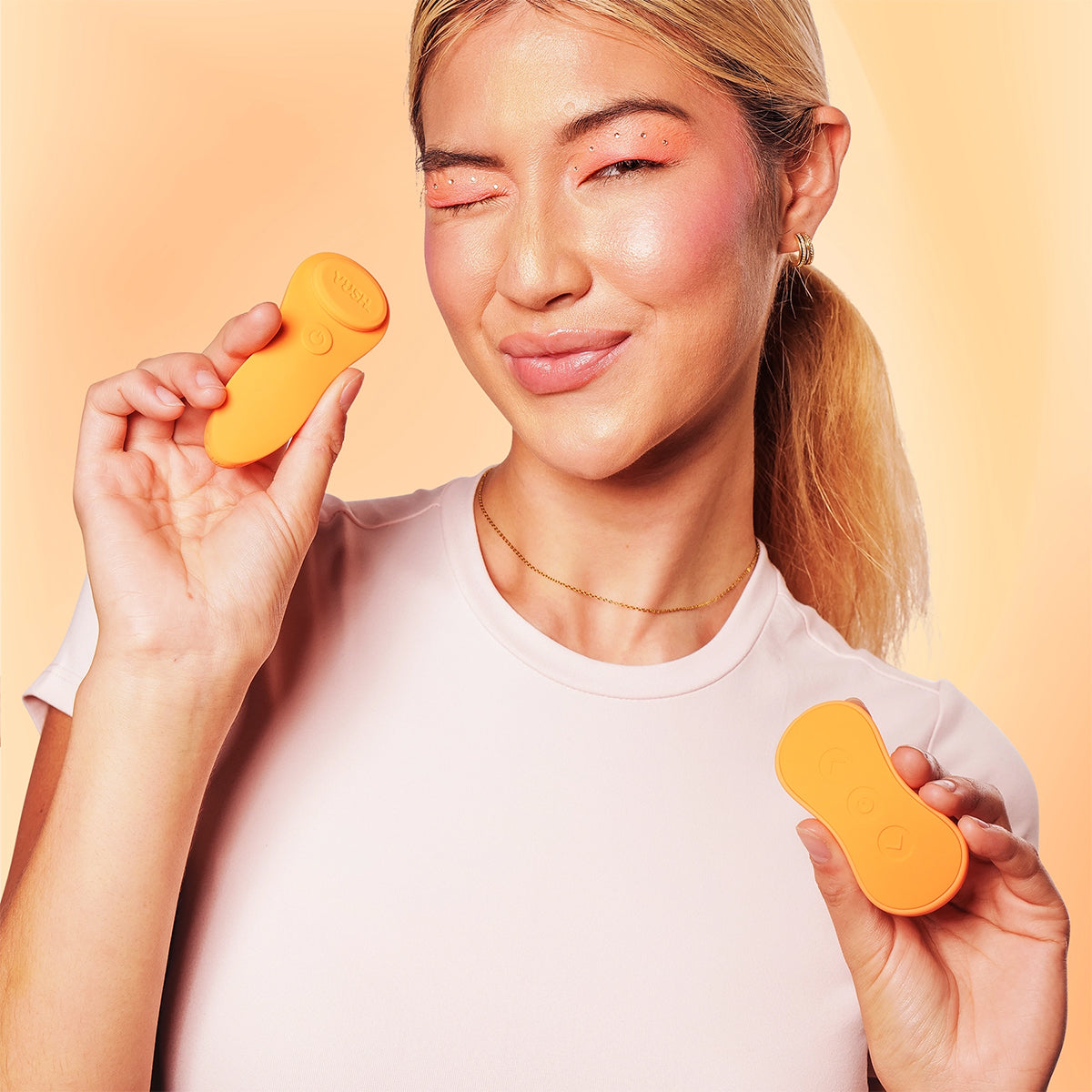 A person holds both the VUSH Luna and the remote control for it. Both of them look to be about the same size and could be nicely gripped and somewhat hidden in a closed fist. | Kinkly